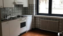 modern kitchen, white cabinets, tile flooring, gas stove, oven, sink, large window, radiator