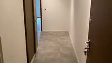 Empty hallway with two doors, tiled floor, white walls, ceiling lights