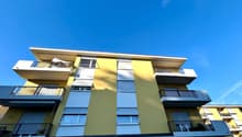 4 story building, yellow and white exterior, multiple balconies, garage