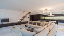 white walls, white floor, large sofa, dining table, television, cabinet with television