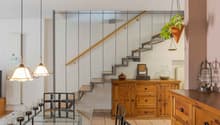 open space living area, stairs, wooden floor, dining table, chairs, kitchen cabinets, chandeliers