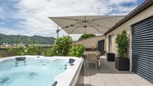 hot tub with umbrella, tiled floor, plants, table, chairs