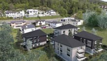 Group of modern townhouses, black rooftops, multiple balconies, surrounded by greenery, hilly background