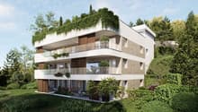 3-story modern apartment building with white exterior, wooden accents, and balconies. The building is surrounded by lush greenery and trees.