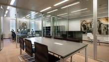 modern office interior with long table, glass walls, chairs, white ceiling, art pieces on the walls