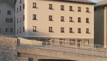 4-story building, beige facade, numerous windows with balconies, stone bridge over a river