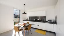modern kitchen, white cabinets, black countertops, stainless steel appliances, dining table, chairs