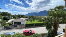 View of a suburban street with mountains in the distance, cars parked, and a house with a garage