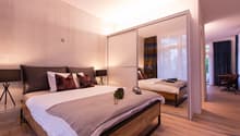 double bed, pillows, blanket, nightstand, lamps, mirror, carpet, wooden flooring