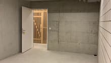 concrete walls, white floor, open door to wooden gate, large room