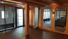 Empty room with wooden beams, tiled floor, glass doors, radiator, surveillance camera
