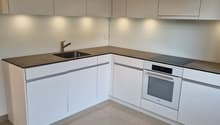 modern kitchen with white cabinets, granite countertop, stainless steel sink, built-in oven and stove, under-cabinet lighting