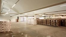 Large warehouse space, high ceilings, pallet racking, stackable boxes, white walls, white lighting, white floor