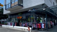 Large building with glass facade, clothing store, metal awning, rack with clothes