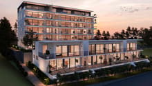 Modern residential building with many glass walls, multiple floors, balconies, trees and shrubs surrounding