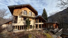 two-storey chalet made of wood, multiple balconies, panoramic windows, located on the hillside with forest and mountain view