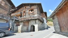 Stone and wooden building, balconies, doors, windows, archway entrance, concrete road