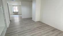 Empty room, hardwood floors, white walls, high ceilings, two columns, windows