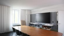 conference room, long wooden table, chairs, mounted TV, curtains, window, floor lamp