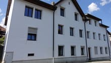 3 story residential building, white facade, multiple windows, brown roof, brick path in front