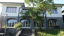 2 story villa, white walls, arched windows, stone base, tree, large balcony, steps, trampoline