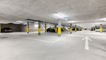 concrete floor, yellow pillars, multiple parking spots, white directional arrows