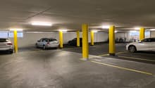 underground parking lot with yellow pillars, 4 cars parked, bicycles parked on the side