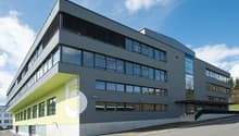 modern office building, gray exterior, glass windows, yellow accents, parking lot