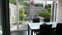 glass doors, large windows, outdoor chairs, dining table, view of the garden