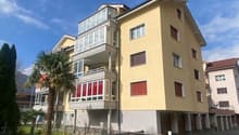 5-story apartment building, yellow exterior, multiple balconies, gated entrance, red-framed windows, red roof