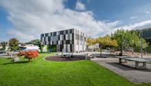 Contemporary architectural building, checkerboard pattern facade, children's playground, trees, bench, table tennis
