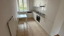white cabinets, tile floor, white table and chairs, large window, gas stove, sink, dishwasher, heating unit