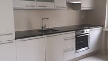 modern kitchen, white cabinets, black countertops, stainless steel appliances, marble floors