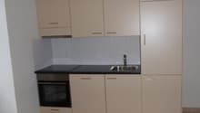 a kitchen with cream cabinets, tiled floor, sink, and oven
