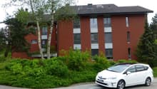 red brick building, 3 stories, white framed windows, balconies, greenery