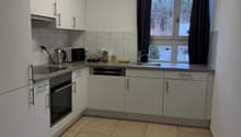modern kitchen with tiled floor, integrated oven, dishwasher, window with curtain