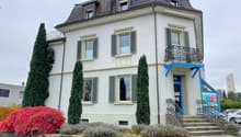 white building, 3 stories, multiple windows, balcony on second floor, entrance stairs