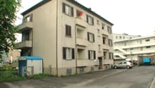 4 story building, balconies, parking lot, small shed