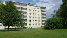 4 story building, yellow exterior, balcony on each floor, green lawn, trees