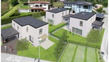 Multiple modern white houses with solar panels on the roofs, surrounded by a well-maintained garden and lawn. There is a parking space visible in the foreground.