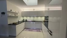 modern kitchen, white cabinets, white tiled floor, black countertops, stainless steel appliances, skylight