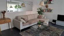 Living room with a beige sofa, glass coffee table, carpet, and a large mirror on the wall.
