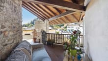 wooden deck with railings, stone wall, potted plants, outdoor furniture, view of the surroundings