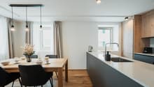 large table with chairs, modern kitchen island, white kitchen cabinets, light fixtures, window with view