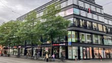 multi-story building, glass windows, parked bicycles, storefronts, pedestrians, urban setting