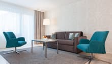 Two armchairs, coffee table, sofa, carpet, bowl of fruit, floor lamp, large window, beige curtain, wall.