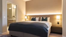 comfortable bed, decorative lamps, wooden floor, large mirror in bathroom, bathtub and sink