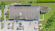 Large building with an attached parking lot and vehicles parked in it.