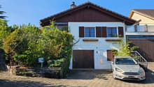 two-story house with a chimney, brown wooden exterior, wooden garage, white base