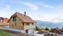 modern chalet style, wooden exterior, brown tiled roof, wooden balcony, chimney, multiple windows, raised ground